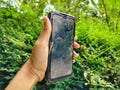 dirty and sratched smartphone screen in hand with green nature background Royalty Free Stock Photo