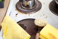 Dirty stove in domestic kitchen with used sponge, leftovers and pots