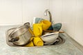 Dirty and unwashed dishes are stacked in the kitchen sink. A mountain of not clean and used tableware.