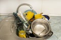Dirty and unwashed dishes are stacked in the kitchen sink. A mountain of not clean and used tableware.