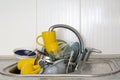 Dirty and unwashed dishes are stacked in the kitchen sink. A mountain of not clean and used tableware.