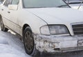 Dirty-white damaged car with a broken bumper