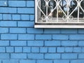 dirty white window with a grille against the background of a blue brick wall. Royalty Free Stock Photo