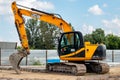 The dirty yellow JCB crawler excavator with bucket at the construction site. Illustrative editorial
