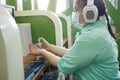 Disability blind person with headphone wearing face mask applying alcohol gel hand sanitizer on hands before using computer with Royalty Free Stock Photo