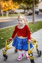 Disability photo of a cute little disabled girl walking with a special walker