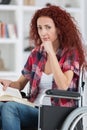 Disabilty and handicap young disabled woman on wheelchair reads book Royalty Free Stock Photo