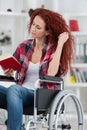 Disabilty and handicap young disabled woman on wheelchair reads book Royalty Free Stock Photo