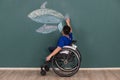 Disable boy on wheelchair showing the atttempt to paint drawing on wall with good attitude