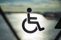 Disable wheelchair sign in public transportation on door glass with the background of sun reflection in the ocean sunset time in Royalty Free Stock Photo