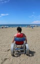 Disabled adult looks at the sea from a wheelchair