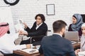 Disabled arab man in wheelchair working in office. Man is doing presentation in fornt of coworkers. Royalty Free Stock Photo