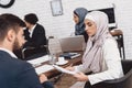 Disabled arab man in wheelchair working in office. Coworkers are discussing notes.