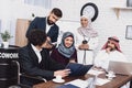 Disabled arab man in wheelchair working in office. Man is sharing notes with coworkers.