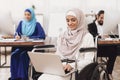 Disabled arab woman in wheelchair working in office. Woman is working on laptop.