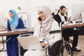 Disabled arab woman in wheelchair working in office. Woman is working on laptop and talking on phone.