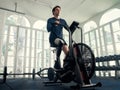 Disabled athlete man riding an airbike in a modern gym