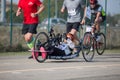 Disabled Athlete who Trains with her Hand Bike with Cyclist and Runners at her Side