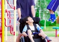 Disabled boy in wheelchair enjoying watching friends play at par Royalty Free Stock Photo