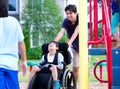 Disabled boy in wheelchair enjoying watching friends play at par Royalty Free Stock Photo