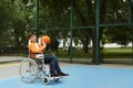 Disabled boy in wheelchair playing basketball  on outdoor court Royalty Free Stock Photo