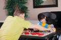 Disabled boy in wheelchair playing checkers with father at home