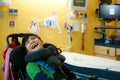 Disabled boy in wheelchair smiling next to hospital bed Royalty Free Stock Photo