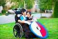 Disabled brother hugging older sister in wheelchair outdoors