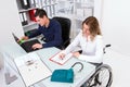 Disabled businesswoman in wheelchair and her colleague Royalty Free Stock Photo