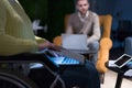 Disabled businesswoman in the wheelchair using her laptop while performing in co-working space. Disability and handicap concept. Royalty Free Stock Photo