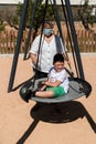 Disabled child in swing set with mother wearing a pandemic coronavirus protective mask Royalty Free Stock Photo