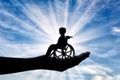 Disabled child in a wheelchair in a man's hand