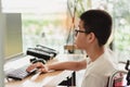 Disabled child on wheelchair wear glasses and working with computer Royalty Free Stock Photo