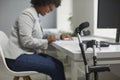 Crutches by office desk with happy disabled female employee working on computer in background