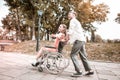 Disabled girl enjoying ride in the park and her boyfriend pushing the wheelchair Royalty Free Stock Photo