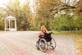 disabled girl in a wheelchair looks at an empty gazebo in an autumn park. View from the back. Royalty Free Stock Photo