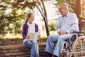 Disabled grandfather in park spending time together with his granddaughter reading book. Royalty Free Stock Photo