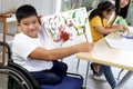 Disabled kids classroom, children having fun during study at school, kids learning together, schoolboy on wheelchair showing his Royalty Free Stock Photo