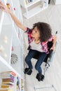 disabled lady struggling to reach book from high shelf