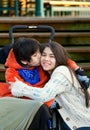Disabled little boy kissing his big sister on cheek while seated Royalty Free Stock Photo