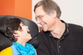 Disabled little boy in wheelchair laughing with father in hospital room Royalty Free Stock Photo