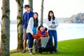 Disabled little boy in wheelchair surrounded by brother and sisters at lakeside. Child has cerebral palsy and children are all bi Royalty Free Stock Photo