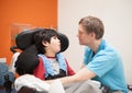 Disabled little boy in wheelchair talking with father in hospital room Royalty Free Stock Photo