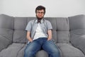 Disabled man with amputated two stump hands sitting on sofa looking at camera.