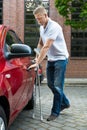 Disabled man holding crutches opening door of a car Royalty Free Stock Photo