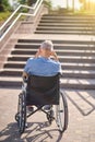 A man in a wheel chair sitting backside near the stairs outdoors