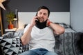 Disabled man with neck brace talking on phone with doctor, experiencing pain while sitting on couch in the living room Royalty Free Stock Photo