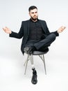 Disabled young man with prosthetic leg sitting on a chair in studio over white background, artificial limb concept Royalty Free Stock Photo