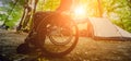 Disabled man resting in a campsite with friends. Wheelchair in the forest