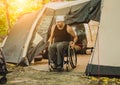 Disabled man resting in a campsite with friends. Wheelchair in the forest